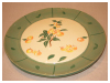 A Bali stoneware cheeseboard plate, decorated with apples and leaves and green border - first pot view.