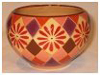 A Bali stoneware round shape bowl, decorated with geometric design with diamond shaps and daisies in autumn colours - first view.