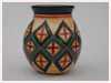A Bali stoneware green vase, decorated with geometric design - four petals in bordered diamond shapes on peach bacgoround - first view.