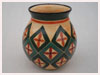 A Bali stoneware green vase, decorated with geometric design - four petals in bordered diamond shapes on peach bacgoround - second view.
