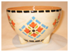 A Bali stoneware bowl with feet, decorated with geometric pattern in pastel colours - third view.