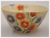A Bali stoneware bowl decorated with blue and orange garden flowers - third view.
